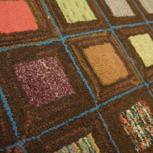 Patchwork-style rug featuring textured multicolor squares outlined in dark brown and vivid blue yarn.