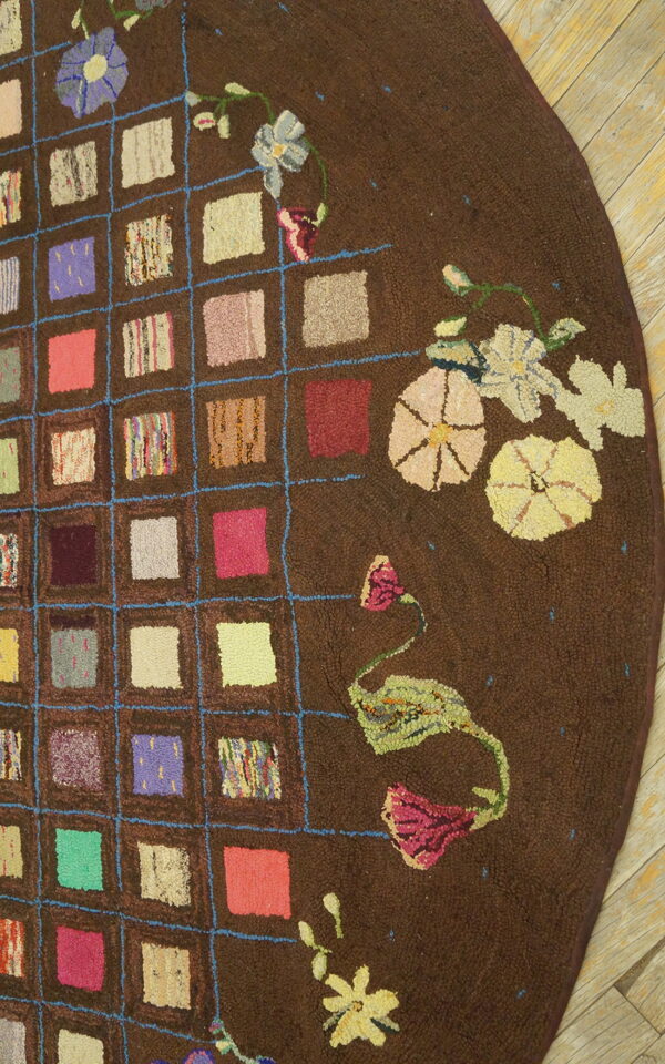 Textured brown round rug with a colorful patchwork grid and scattered pastel flowers on wood planks.