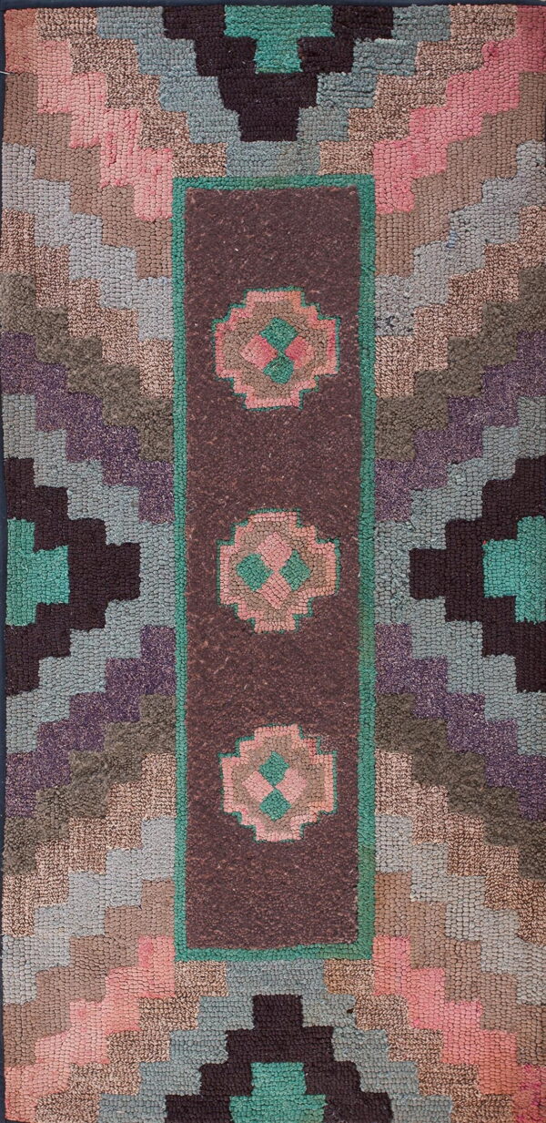 Multi-colored hooked rug featuring a central maroon band with pink and teal stylized floral shapes.