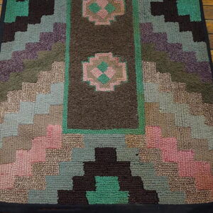 Textured geometric rug runner in teal, brown, dusty pink, and olive, featuring medallions on a rustic wood floor.