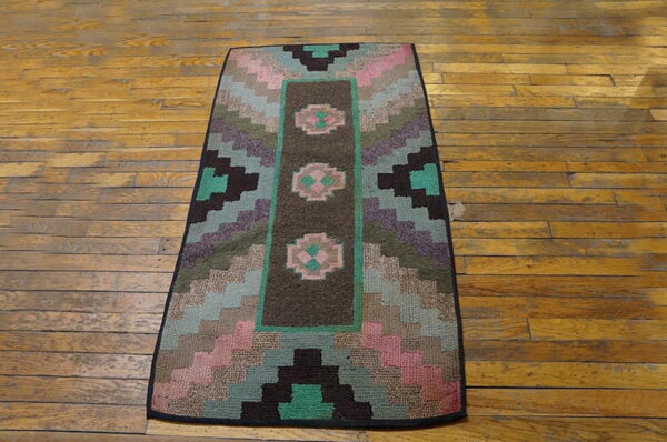 A low-pile runner featuring geometric pink, teal, and purple patterns on a dark brown field, resting on hardwood floors.