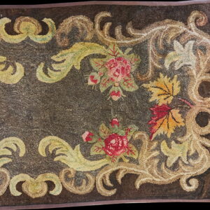 Looped rug detail features a dark brown field bordered by beige scrolls, red roses, and yellow autumn leaves.