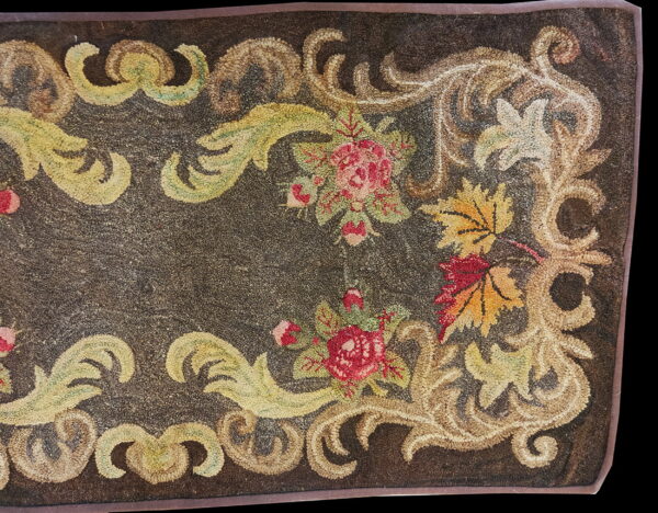 Looped rug detail features a dark brown field bordered by beige scrolls, red roses, and yellow autumn leaves.