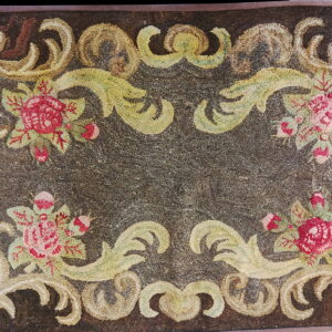 Textured dark brown rug featuring a border of pink roses and light green and beige scrolling foliage.
