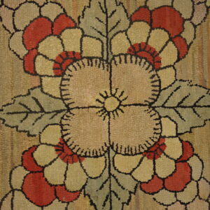 Close-up of a textured rug with red and tan flowers, sage leaves, and a striated golden background.