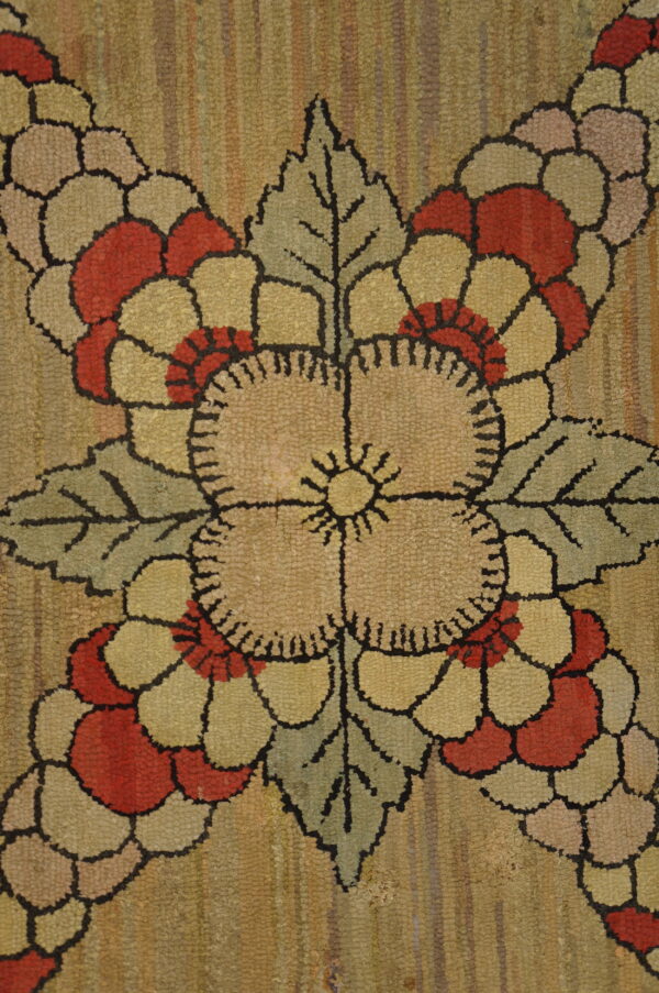 Close-up of a textured rug with red and tan flowers, sage leaves, and a striated golden background.