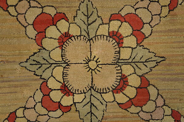 Close-up of a textured beige rug with large red, khaki, and sage floral motifs outlined in black.