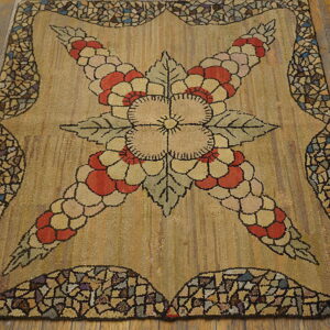 Highly textured tan rug featuring a central red and cream flower motif and a multicolored cobblestone border.