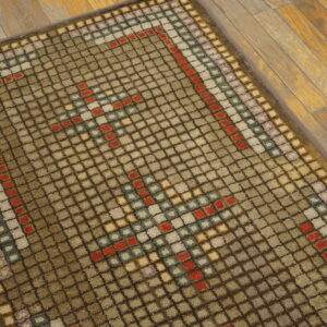 This brown and beige high-pile rug features a multi-colored geometric square pattern on wooden flooring.
