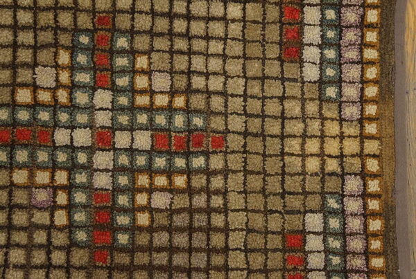 The square-grid texture of this rug features brown, tan, red, blue, and purple accents.