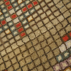 Close-up of a high-pile rug with a beige and brown diagonal grid pattern and colorful squares of red, blue, and cream.