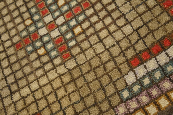 Close-up of a high-pile rug with a beige and brown diagonal grid pattern and colorful squares of red, blue, and cream.