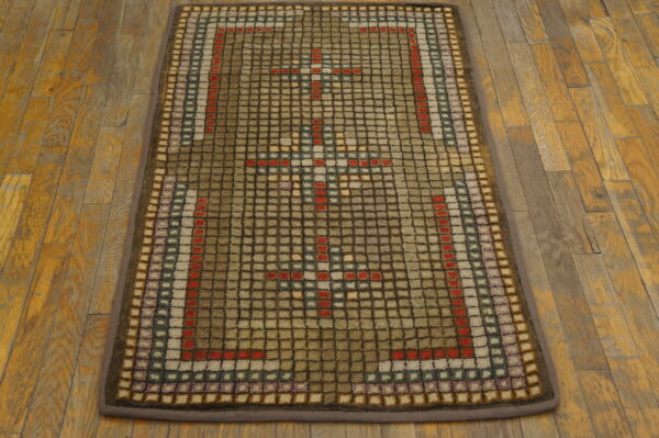 Muted brown runner rug with a thick squared pattern in tan, red, and blue on distressed wood.