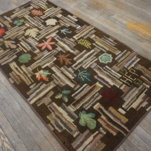 Rustic dark brown rug with a textured stripe and multicolored leaf pattern on gray wood flooring.