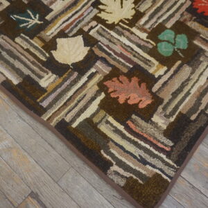Textured brown rug with multicolored geometric log cabin strips and autumn leaf accents rests on weathered wood floors.