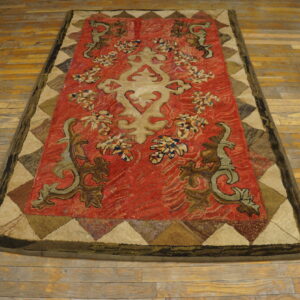 Red textured rug featuring a beige stylized medallion and scrolling brown and olive motifs on wood flooring.
