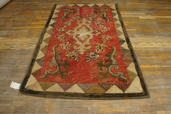 Red textured rug featuring a beige stylized medallion and scrolling brown and olive motifs on wood flooring.