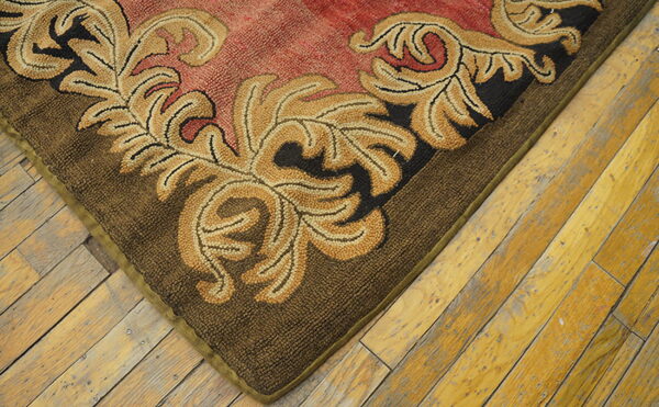 Textured rug corner features gold scrolling on a red field and a dark brown border over distressed wooden planks.