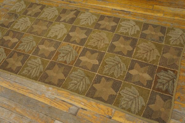 Brown and green runner with leaf and star patchwork pattern lies on worn plank wood floor.