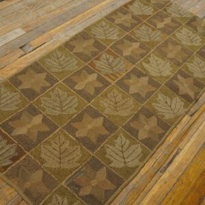 Brown and green textured runner rug featuring leaf and star diamond patterns on wood planks.