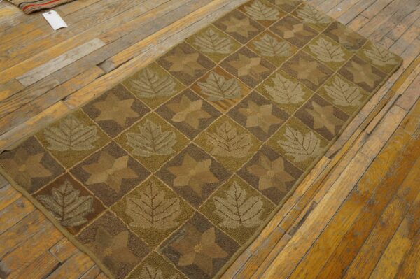 Brown and green textured runner rug featuring leaf and star diamond patterns on wood planks.