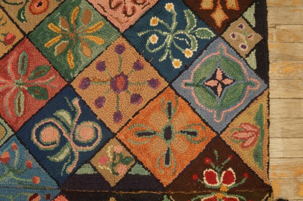Detailed view of a brightly colored, chunky hooked rug with floral patchwork on light wood planks.