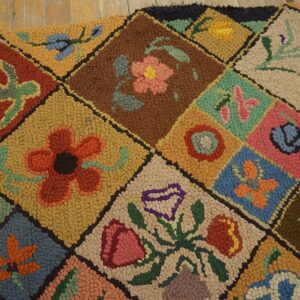 Textured floral hooked rug featuring colorful diamonds in pink, blue, rust, and gold on rustic wood planks.