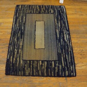 Textured rectangular rug featuring dark striped borders and a light gradient center on rustic wood flooring.
