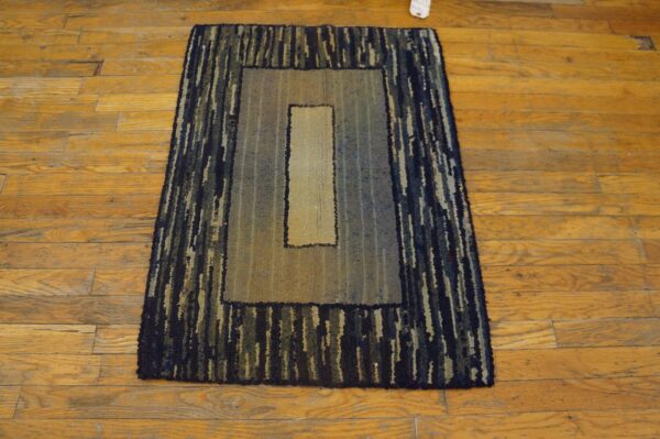 Textured rectangular rug featuring dark striped borders and a light gradient center on rustic wood flooring.
