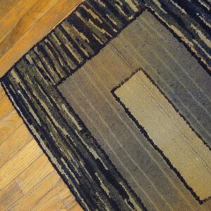 Coarse, textured rug with navy and tan geometric borders rests on a diagonal wood plank floor.
