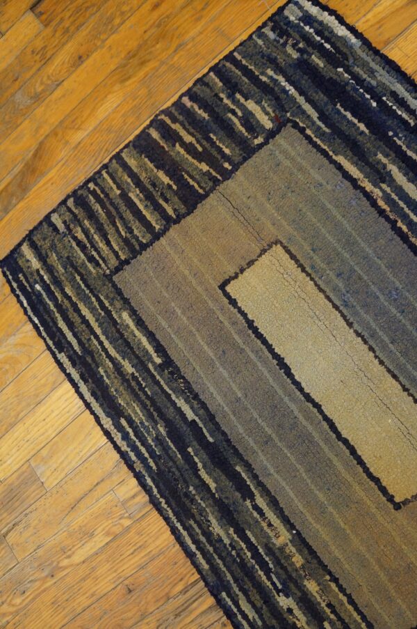 Coarse, textured rug with navy and tan geometric borders rests on a diagonal wood plank floor.