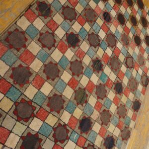 A textured rug with multicolored diamond checks and brown star medallions rests on light wood floors.