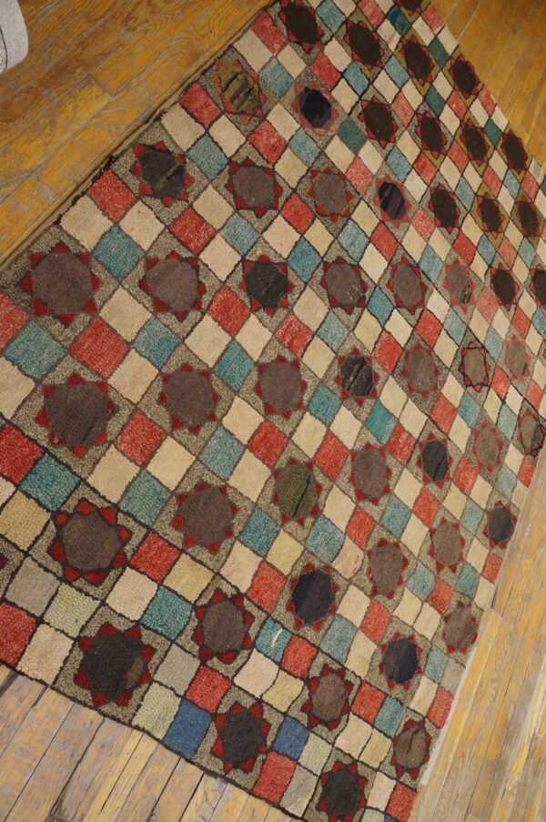 A textured rug with multicolored diamond checks and brown star medallions rests on light wood floors.