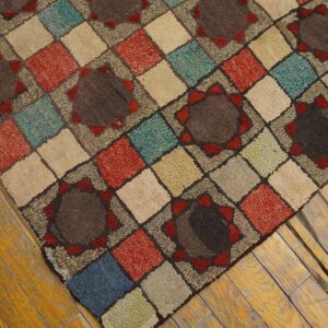 A multi-colored, textured rug with a diamond and medallion pattern sits on worn hardwood planks.