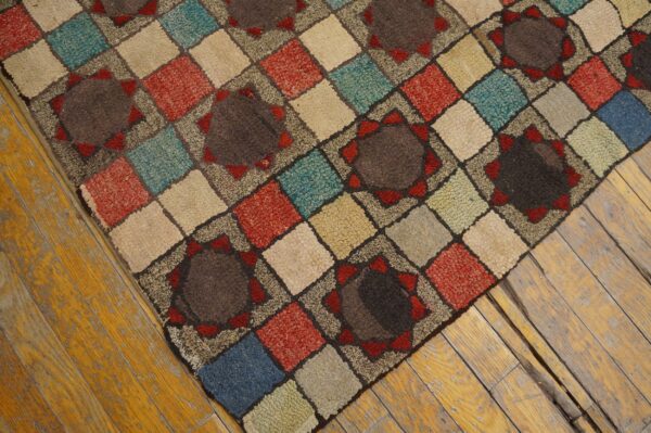 A multi-colored, textured rug with a diamond and medallion pattern sits on worn hardwood planks.