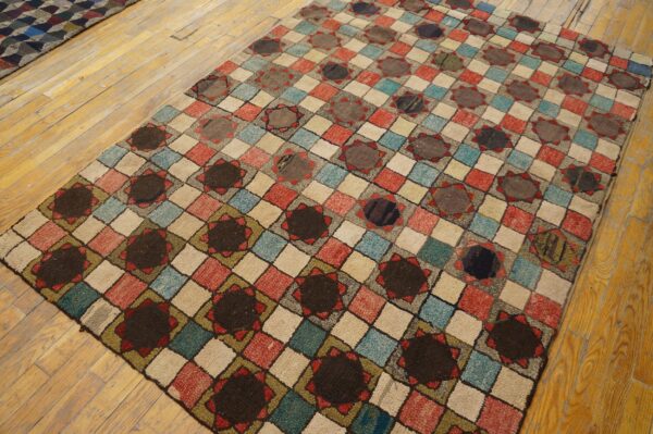 Multicolored diamond grid rug with dark circular motifs rests on a rustic yellow wood plank floor.