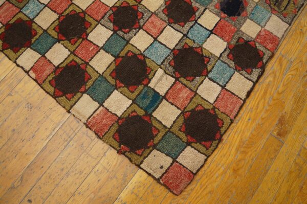 Geometric high-pile rug in brown, red, teal, and cream diamonds rests on worn wooden planks.