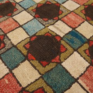 Multi-colored diamond grid rug with chunky texture, featuring dark star-shaped medallions on a wood floor.