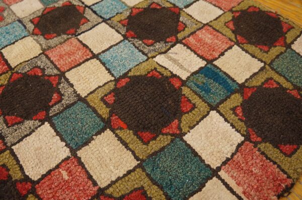 Multi-colored diamond grid rug with chunky texture, featuring dark star-shaped medallions on a wood floor.