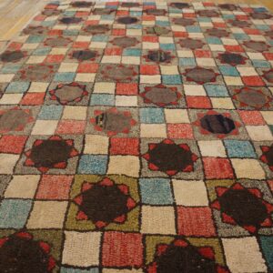 Multicolored high-pile rug featuring a geometric checkerboard and dark star pattern on wood planks.