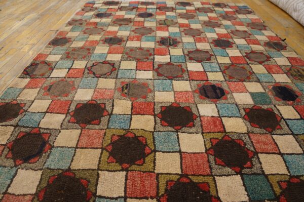 Multicolored high-pile rug featuring a geometric checkerboard and dark star pattern on wood planks.