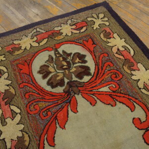 Textured, looped rug showing a central floral medallion and scrolling borders in red, brown, tan, and olive.