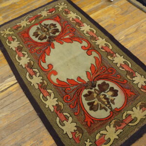 Textured low-pile rug with red, brown, and sage floral patterns lying on distressed yellow wood plank flooring.