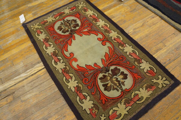 Textured low-pile rug with red, brown, and sage floral patterns lying on distressed yellow wood plank flooring.