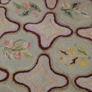 Textured rug featuring a blue-gray field, geometric maroon outlines, and pastel pink and yellow floral sprigs.