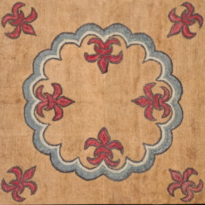 Tan hooked rug featuring a blue-gray scalloped medallion border and red stylized floral motifs.