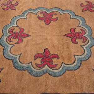 Tan, medium-pile rug with a blue central medallion and red stylized flowers on wood floor.