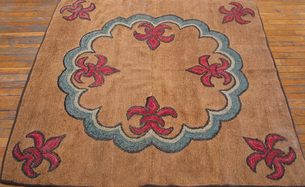 Tan, medium-pile rug with a blue central medallion and red stylized flowers on wood floor.