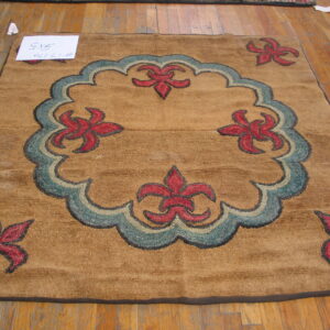 Square tan rug with low, chunky texture, featuring red and teal curvilinear floral designs on wood flooring.
