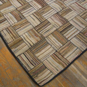 Multi-toned textured rug with a striped block pattern and dark border on honey-toned wood floors.